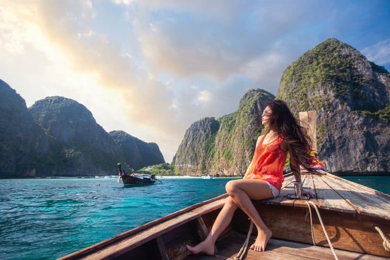 asian travel woman relax traditional long tail boat with maya bay background phi phi