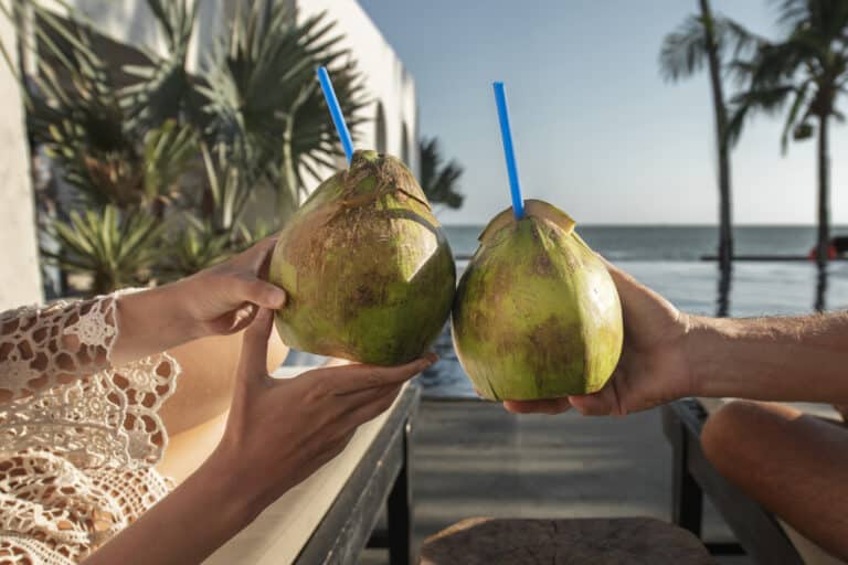 Notre Blog 1 couple talking drinking coconut milk by pool during vacation